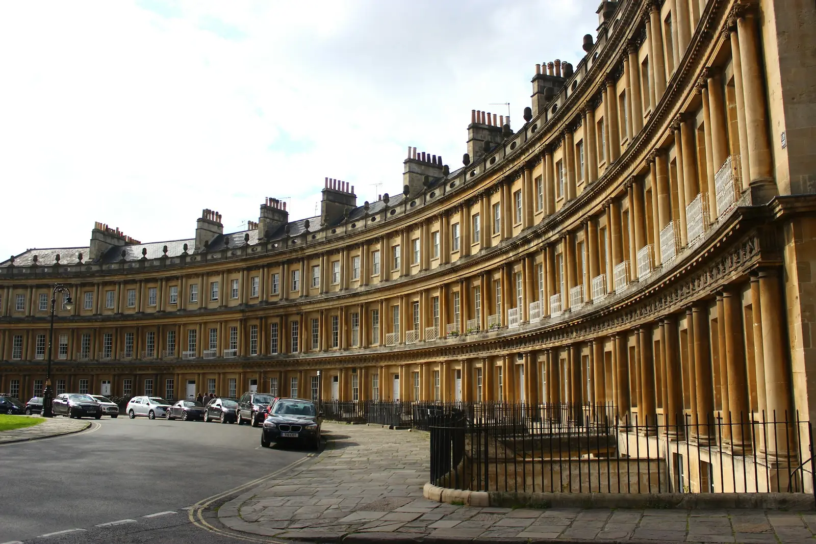 Couple walking on the grass below the curved Georgian façade of the Royal Crescent, Bath