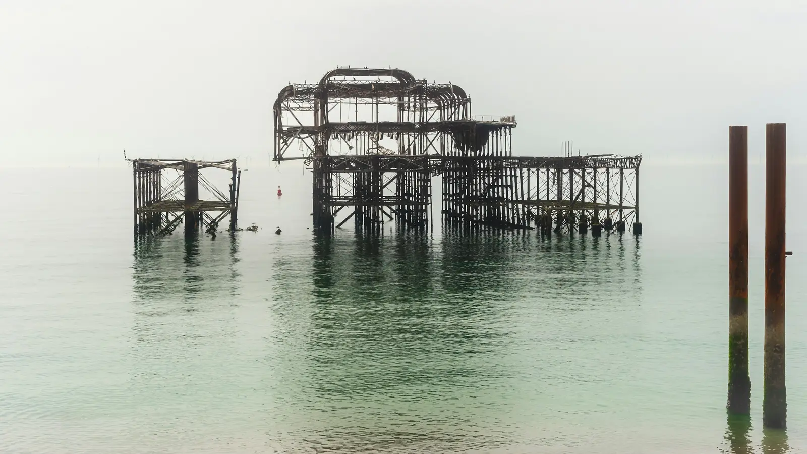 Couple on Brighton beach at dusk with the West Pier ruins silhouetted behind them