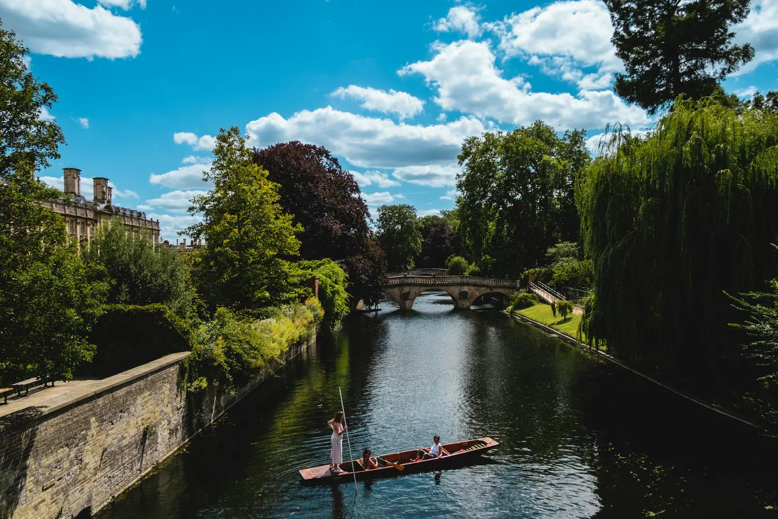 Couple in a punt on the River Cam passing college lawns on the Backs in Cambridge