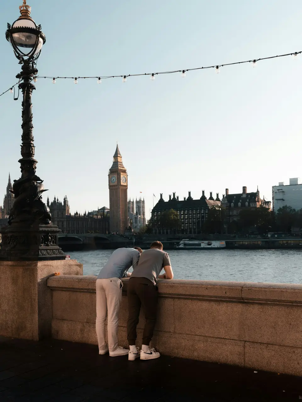A man on one knee proposing to his partner on a riverside path